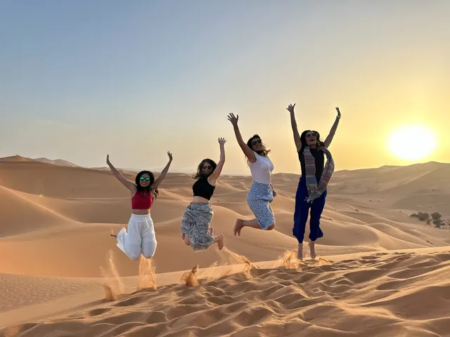 Viajeros saltando en las dunas del Erg Chebbi al atardecer, Merzouga, Marruecos