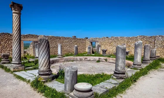 Ruínas romanas de Volubilis com colunas antigas sob um céu azul no Marrocos